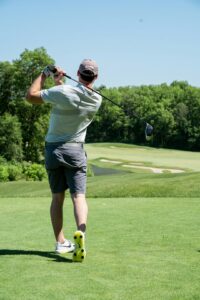Golfer performing a controlled rotational warm-up beside a golf bag before practicing swings.