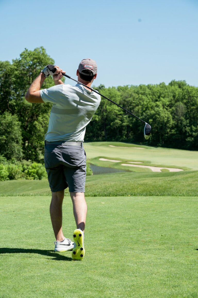 Golfer performing a controlled rotational warm-up beside a golf bag before practicing swings.